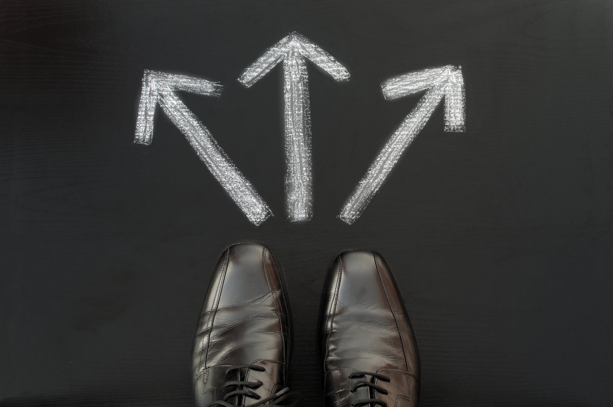 Businessman's shoes with arrows on the ground pointing in different directions