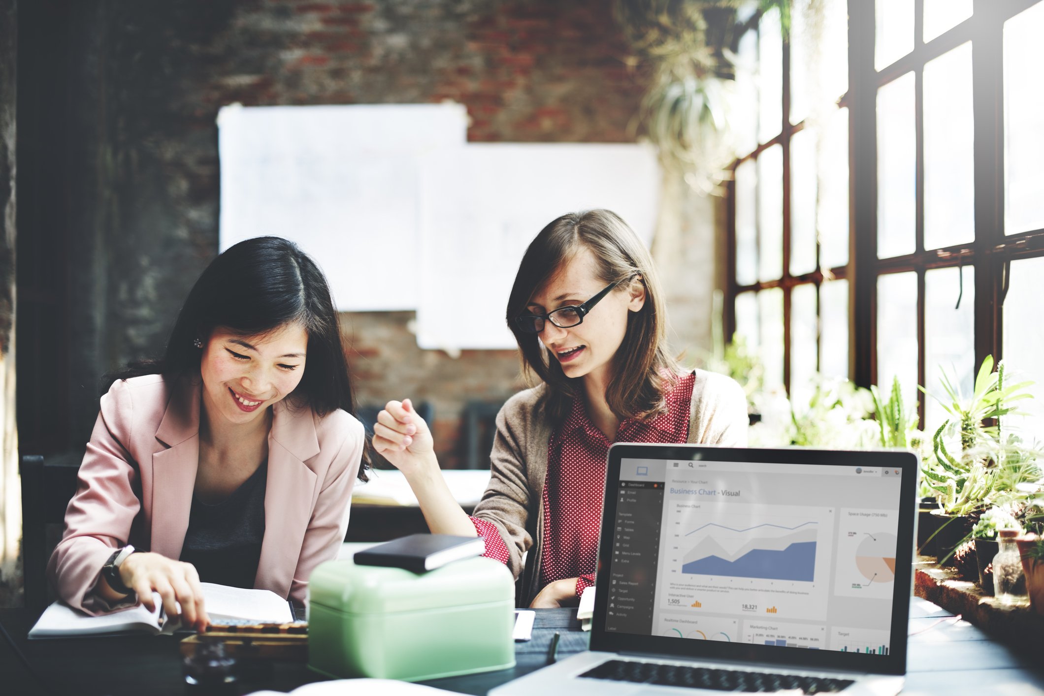 Two business women looking at online traffic graphs 